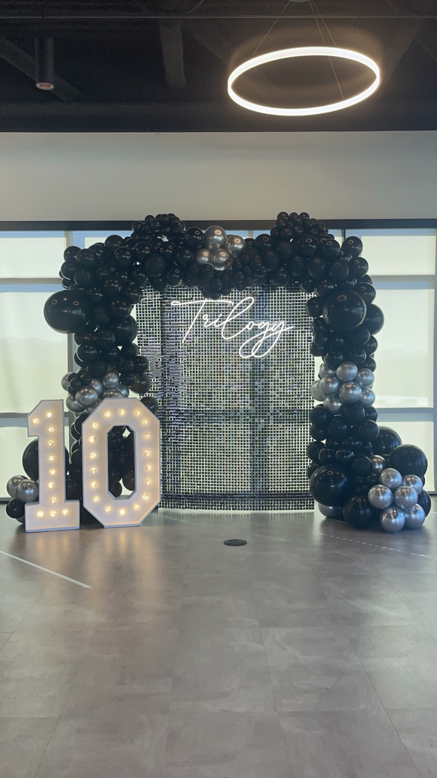 Dozen Roses Events black and silver balloon backdrop with illuminated marquee numbers
